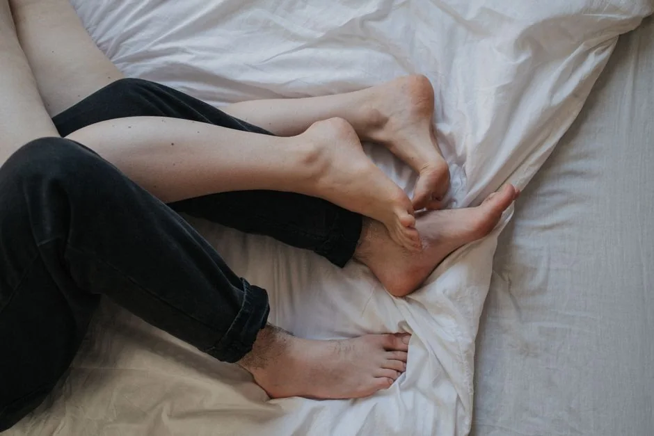 Piernas entrelazadas entre sábanas blancas
